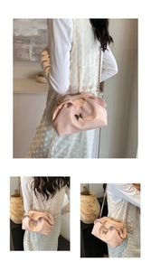 Detail of light pink pleated cloud bag featuring a silver butterfly buckle and chain strap