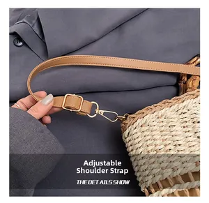 Detail showing the adjustable brown leather strap and gold hardware on a straw bag