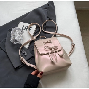 Vue détaillée du petit sac à dos rose poudré avec nœud et finition nacrée sur veste