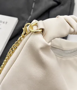 Detailed macro view of the cream-colored pleated leather bag with gold metal chain link