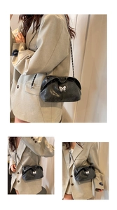Detail of glossy black pleated cloud bag featuring silver butterfly buckle and chain strap