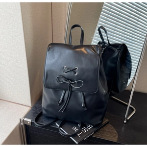 Détail du sac à dos en PU noir brillant avec œillets de laçage et nœud décoratif