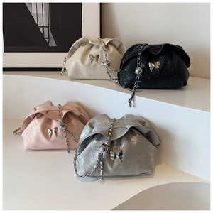 Detail view of cloud bag with metallic butterfly buckle and leather chain strap