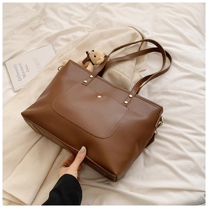 Detail einer dunkelbraunen Shopper-Tasche mit Fronttasche und niedlichem Bären-Anhänger