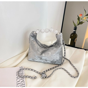 Macro view of silver metallic bag with clear bead handle on white wrinkled fabric