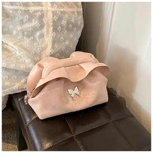 Macro view of pink ruched cloud bag with pearlescent finish and silver butterfly charm