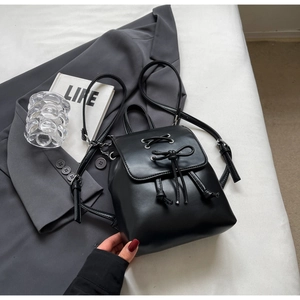 Détail d'un sac à dos noir en similicuir avec rubans lacés et nœud décoratif élégant
