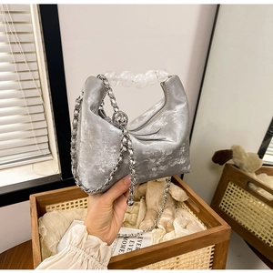 Detail of silver metallic pleated handbag featuring large transparent beaded top handle