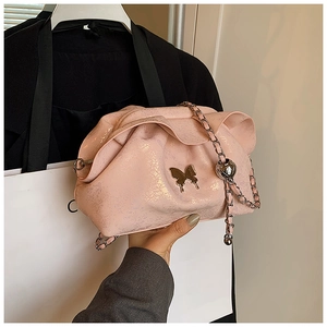 Close-up of pink ruched cloud bag featuring metallic butterfly clasp and chain detail