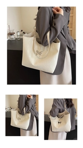 Macro detail of cream tote bag featuring textured leather and a silver bow clasp accent