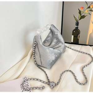 Detail of silver geometric handbag with acrylic beaded handle and metal chain strap