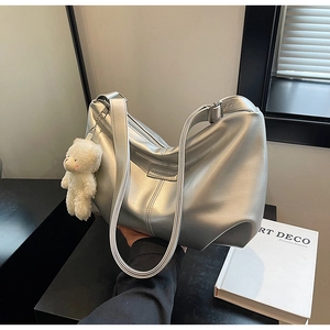 Detail of silver metallic tote bag with adjustable strap and cute plush bear charm decoration