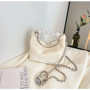 Close-up of cream crescent bag with large clear beads handle and metal chain strap