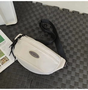 Détail du sac bandoulière en nylon blanc avec sangle noire et étiquette BOKABAG