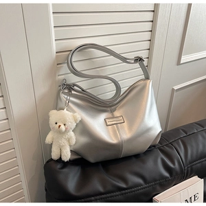 Detailed view of a silver metallic tote bag with a zipper and white plush bear charm