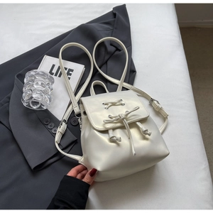 Détail d'un mini sac à dos blanc perle avec laçage en ruban et fermeture à cordon coulissant