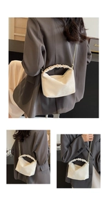 Close-up of pleated handle and gold chain detail on creamy white cloud bag