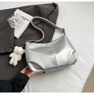 Detail of silver metallic tote bag with smooth texture and cute white plush bear charm