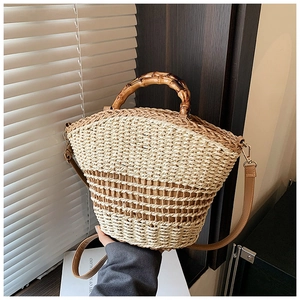 Detail of straw woven bucket bag featuring bamboo handle and contrast texture design