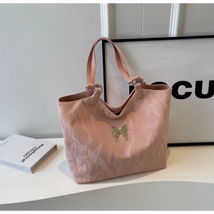 Detail of pink tote bag showing unique pleated texture and silver metallic butterfly logo