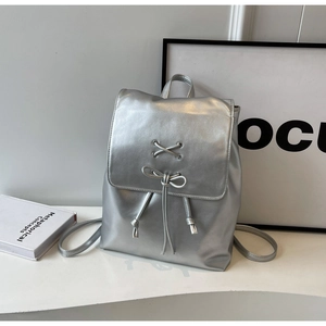 Détail du sac à dos argenté métallisé avec cordon à nœud et design à lacets croisés