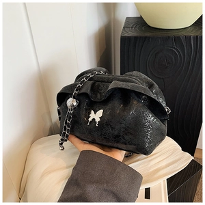 Detail of black pleated cloud bag with silver butterfly charm and chain strap