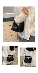 Detail view of black pleated cloud bag with gold chain strap and textured handle
