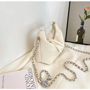 Detail of cream beaded handle and suede texture on a curved crossbody handbag