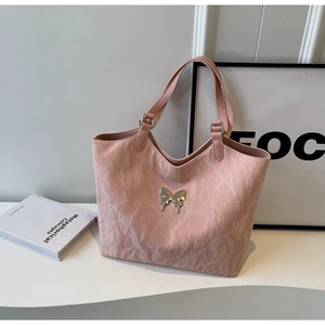 Detail of pink bow tote bag showing unique textured fabric and silver butterfly charm