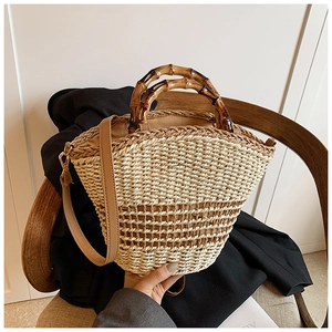 Detail of the woven straw bucket bag with vintage polished bamboo top handle and leather strap
