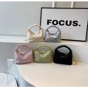 Detail of elegant pleated handles and glossy satin finish on stylish chain handbags
