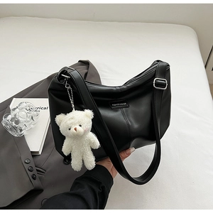 Detail of black matte leather dumpling bag featuring a plush bear and silver hardware
