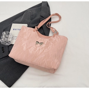 Detail of pink wrinkled tote bag featuring a metallic liquid-style bow and shoulder straps