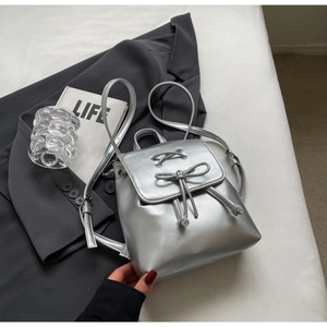 Détail d'un mini sac à dos argenté métallisé avec ruban nœud et design à cordon