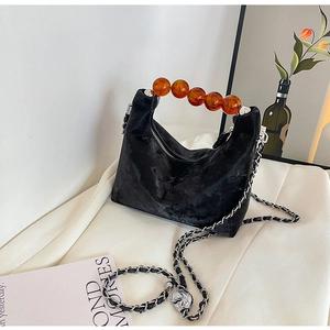 Detail of black velvet trapezoid bag with amber resin beaded handle and metal chain