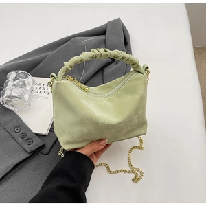 Close-up of mint green pleated handbag with golden chain and matte leather texture