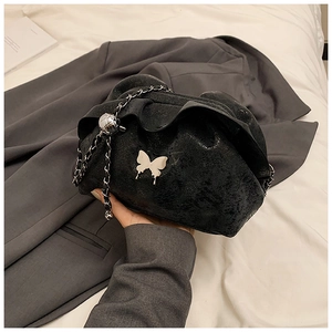 Close-up of black cloud bag featuring silver butterfly buckle and woven chain strap