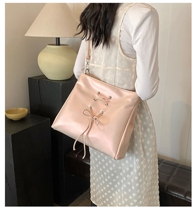 Detail of a large pink shoulder bag with ballet-style bow and smooth leather texture