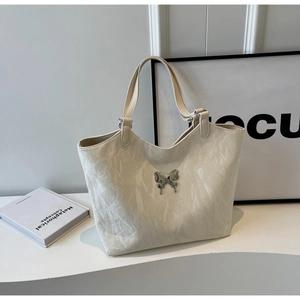 Detail shot of white tote bag featuring a silver butterfly relief and pleated texture