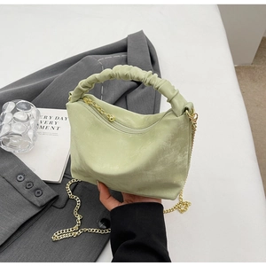 Detail of mint green pleated handbag featuring golden chain strap and soft matte texture