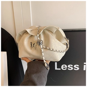 Macro view of creamy white pleated cloud bag with silver butterfly buckle and chain