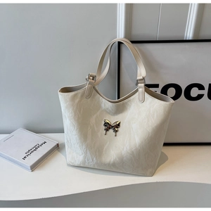Detailed close-up of cream textured tote bag featuring a silver butterfly metallic buckle