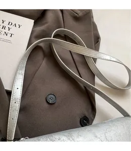 Detail of silver shoulder bag showing adjustable thin strap with multiple buckle holes