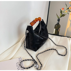 Detailed shot of black velvet hobo bag with amber beaded handle and chain strap