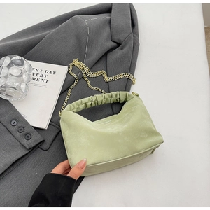 Close-up of light green pleated handbag featuring soft matte texture and gold chain strap