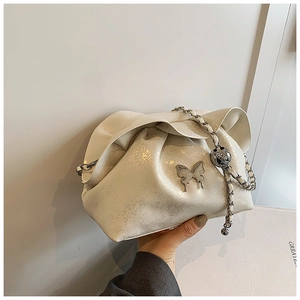 Detail of white pleated cloud bag with silver butterfly charm and metal chain strap