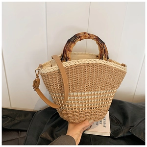 Detail of hand-woven straw bucket bag featuring bamboo handles and white stripes
