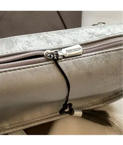 Close-up of silver embossed texture and metal zipper with tassel on the underarm bag