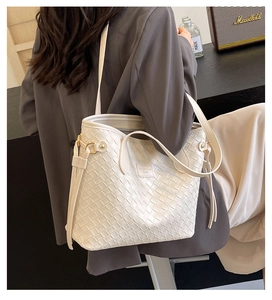 Detailed view of beige woven tote bag showing fine square texture and shoulder strap