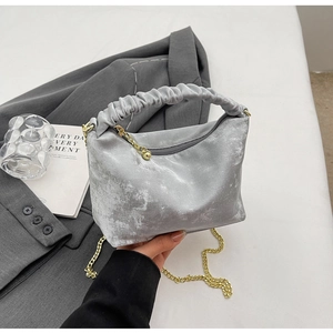 Close-up of silver velvet pleated handbag with golden ball zipper and chain strap